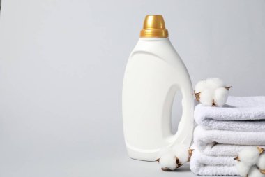 Açık gri arka planda kumaş yumuşatıcı, havlu ve pamuk çiçekleri, metin için boşluk