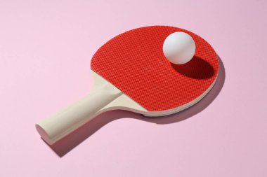 Pembe arka planda pinpon raketi ve top, yakın plan.