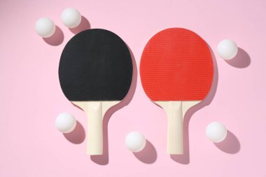 Masa tenisi raketleri ve pembe arka planda toplar, düz yatıyordu.