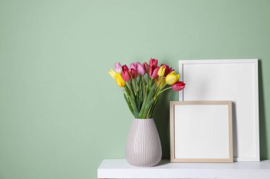 Renkli duvarın yanındaki masada bir buket güzel lale ve çerçeve. Metin için boşluk