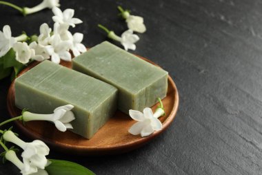 Siyah masada sabun ve yasemin çiçekleri, yakın plan. Metin için boşluk