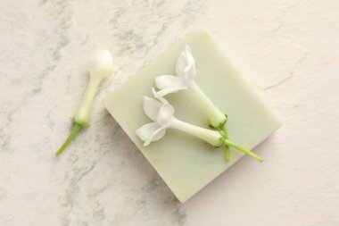 Bir kalıp sabun ve yasemin çiçekleri ışık masasında, düz yatıyordu.