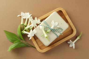 Açık kahverengi arka planda sabun ve yasemin çiçekleri, düz uzanmış.