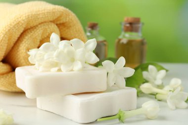 Sabun kalıpları, yasemin çiçekleri ve beyaz mermer masada havlu, yakın plan.