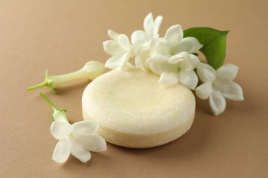 Açık kahverengi arka planda sabun ve yasemin çiçekleri, yakın plan.