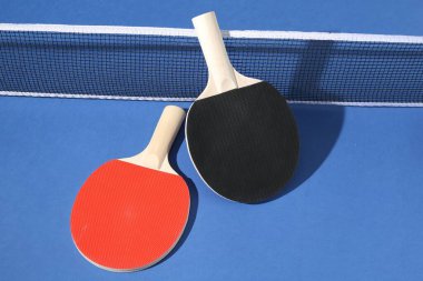 Masa tenisi raketleri ve mavi arkaplanda ağ.
