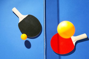 Masa tenisi raketleri, toplar ve ağ mavi arka planda, düz yatıyordu.