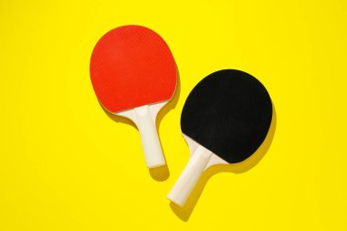 Sarı zemin üzerinde pinpon raketleri, üst görünüm