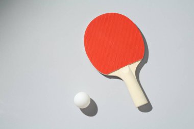Masa tenisi raketi ve topu arka planda, üst görünümde.