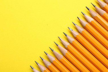 Sarı arka planda keskin grafit kalemler, düz. Metin için boşluk
