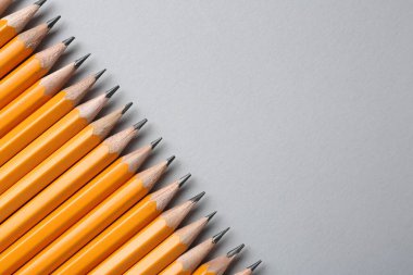 Gri arka planda keskin grafit kalemler, düz. Metin için boşluk