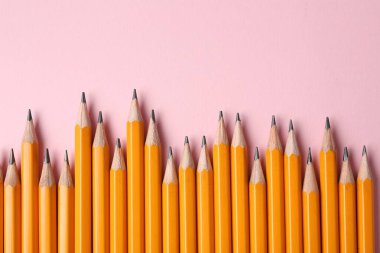 Pembe arka planda keskin grafit kalemler, düz yatış. Metin için boşluk