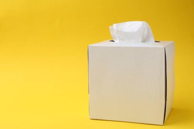 Sarı arka planda kağıt mendillerle dolu bir kutu. Metin için boşluk