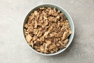 Kase içindeki kuru hindiba kökleri gri desenli masa, üst manzara.