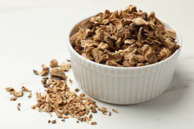 Beyaz masadaki kasede kurumuş hindiba kökleri, yakın plan.