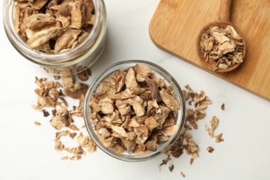 Kuru hindiba kökleri kasede, kavanoz ve kaşık beyaz masada, düz yatıyordu.