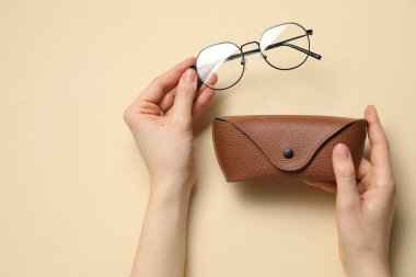 Gözlüklü ve çantalı kadın bej arka planda, üst manzara