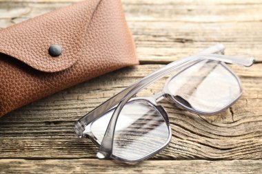 Şık gözlükler ve çanta ahşap masada, yakın plan.