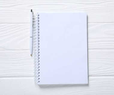 Kalem ve açık defter beyaz ahşap masa, üst görünüm
