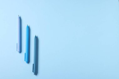 Açık mavi arka planda şık kalemler, düz yatış. Metin için boşluk