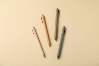 Bej arka planda şık kalemler, düz yatış