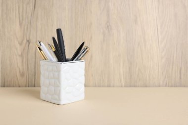 Tahta arka planda, bej masadaki tükenmez kalemler. Metin için boşluk