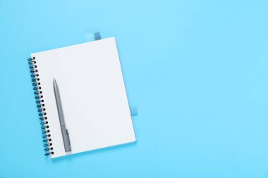 Kalem ve defter açık mavi arka planda, en üstte. Metin için boşluk