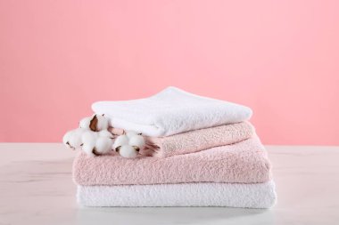 Temiz havlular ve pamuk çiçekleri açık mermer masa üzerinde pembe arka plana karşı