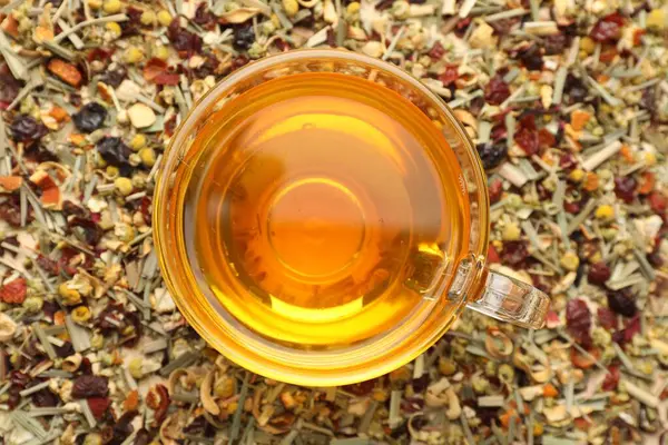 Kuru yaprakların üzerinde cam bardakta lezzetli bitkisel çay.