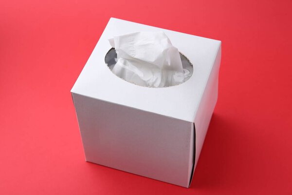Box with paper handkerchiefs on red background, closeup