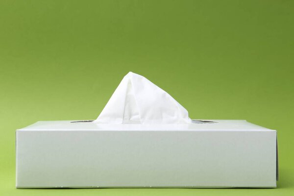 Box with paper handkerchiefs on green background. Space for text