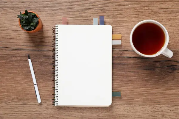 Kalem, defter, renkli çıkartmalar, çay ve çiçek dekoru ahşap masa, düz uzanma