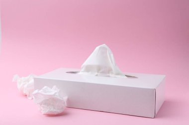 Kağıt mendilli bir kutu ve pembe arka planda buruşmuş mendiller. Metin için boşluk