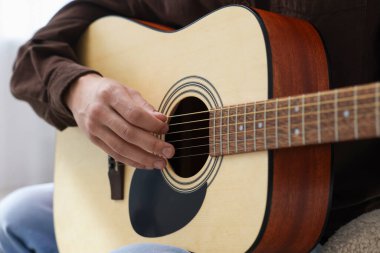 Sandalyede gitar çalan adam, yakın plan.