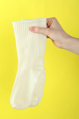 Sarı arka planda bir çift çorap olan kadın, yakın plan.