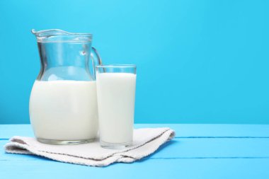 Bardakta taze süt ve açık mavi ahşap masada sürahi. Metin için boşluk