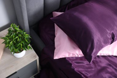 Lüks ipek çarşaflar yatağın üzerinde ve komodinin üzerinde.