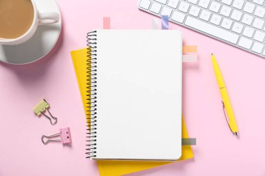 Renkli çıkartmalar, diğer kırtasiye malzemeleri, pembe zemin üzerinde kahve ve bilgisayar klavyesi olan boş bir defter aç, düz uzan