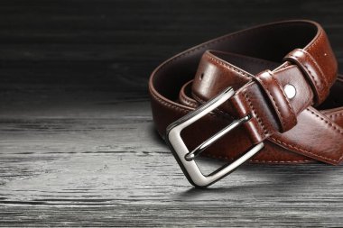 Tahta masada kahverengi bir deri kemer, yakın plan. Metin için boşluk