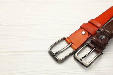 Beyaz ahşap masanın üzerinde iki deri kemer, manzaranın üstünde. Metin için boşluk