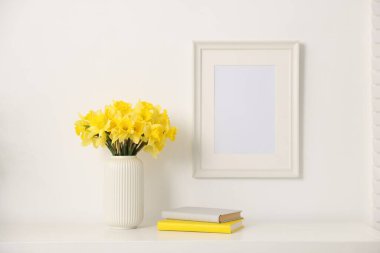 Vazodaki güzel nergisler ve evdeki beyaz dolaplarla ilgili kitaplar.