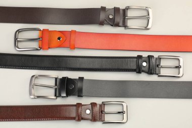 Beyaz arka planda bir sürü deri kemer, düz uzanmış.