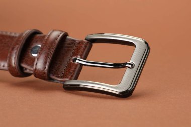 Soluk kahverengi arka planda bir deri kemer, yakın plan.