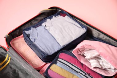 Pembe arka planda paketleme küpleri olan bavulu aç, kapat