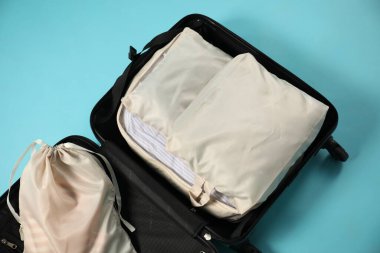 Açık mavi zemin üzerinde paketleme küpleri olan bavulu aç, üst görünüm