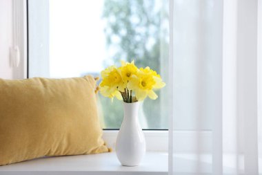 Evdeki pencere eşiğinde vazodaki güzel nergisler