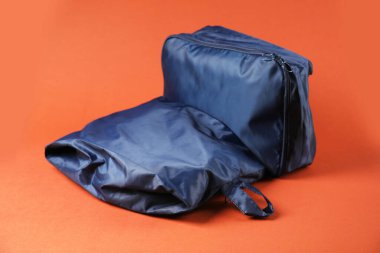 Parlak turuncu arka planda giysileri olan küpleri paketlemek, yakın plan