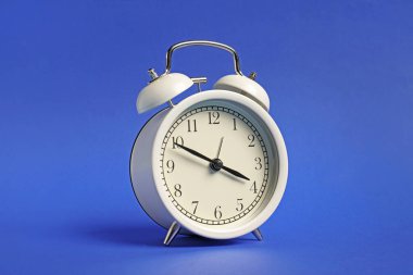 Mavi arkaplanda bir beyaz alarm saati