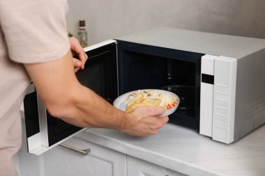 Yemek tabağını mikrodalgaya koyan adam, yakın plan.