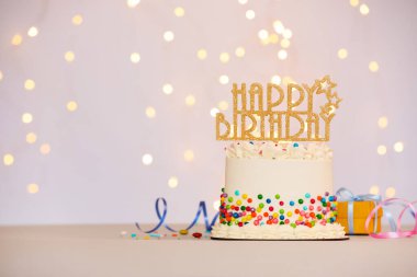 Renkli süslemeli lezzetli bento keki, süs eşyası ve diğer şenlik dekorları açık arka planda, yazı için yer var. Bokeh etkisi